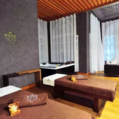 Deux tables de massage au spa de l'hôtel avec un jacuzzi au fond  