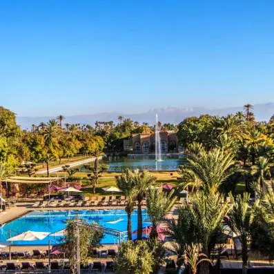 Vue d'ensemble de l'hôtel sur la partie extérieur, piscine, fontaine et jardin avec le bâtiment de l'hôtel