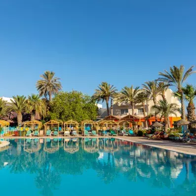 Piscine extérieure turquoise entourée de cabanas jaunes, transats bleus et palmiers sous un ciel ensoleillé.