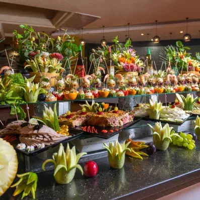 Buffet d’amuse-bouches artistiques avec brochettes, fruits sculptés et présentations culinaires décoratives.