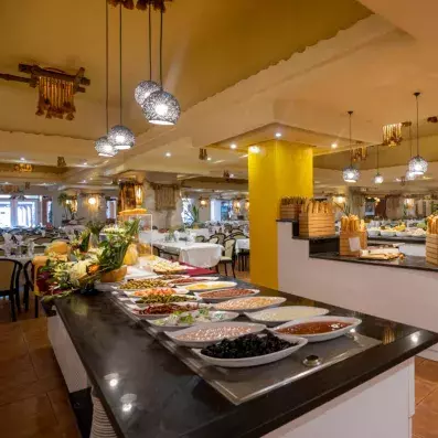 Buffet de restaurant avec plats variés, décorations fruitées et tables dressées dans une salle lumineuse.