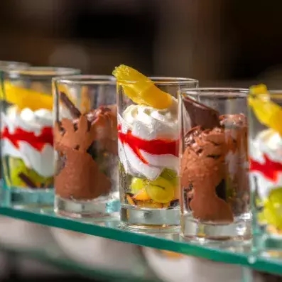 Verrines dessert colorées avec mousse, fruits frais et coulis rouge en présentation soignée.