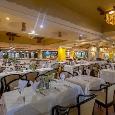 Salle de restaurant élégante avec tables dressées, éclairage chaleureux et buffet en arrière-plan.