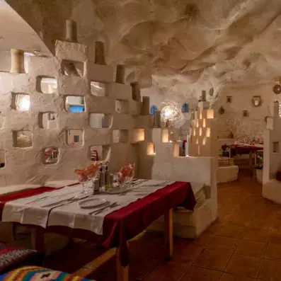 Restaurant décoré façon grotte avec murs sculptés, tables dressées et ambiance chaleureuse.