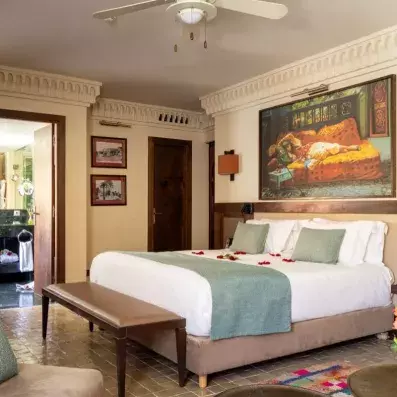 chambre avec grand lit double, salle de bain au fond , tapis colorés