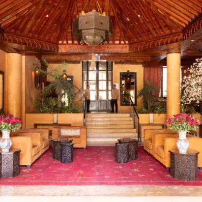 entrée de réception avec tapis rouge & escalier avec des salons en beige