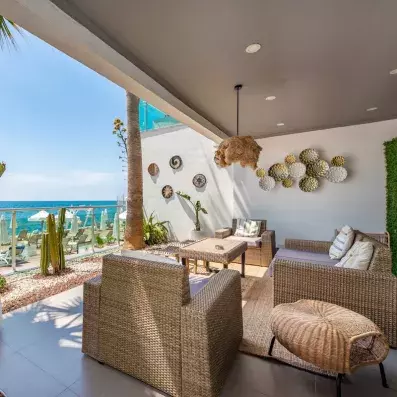 terrasse avec canapés et fauteuil en osier face à la mer