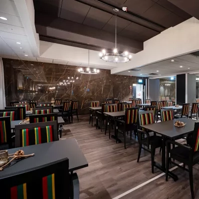 Salle de restaurant spacieuse de l'Hôtel Sodankylä avec chaises colorées et décoration lapone.