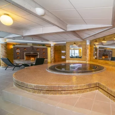 Espace bien-être avec jacuzzi et cheminée au Grand Arctic Resort, détente lors d'un voyage en Laponie.