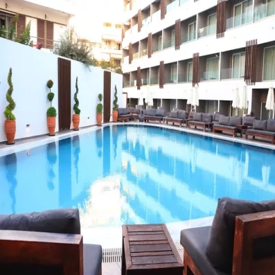 Piscine, terrasses des chambres, transats, arbustes, bâtiment de l'hôtel