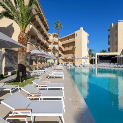 beau temps, transats au bord de la piscine, parasols, palmiers, bâtiment de l'hôtel