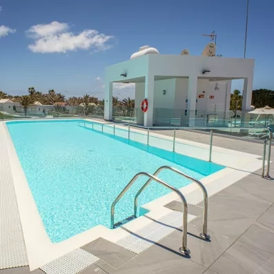 Une piscine sous un ciel bleu, équipée d'une rampe d'accès et d'une échelle.