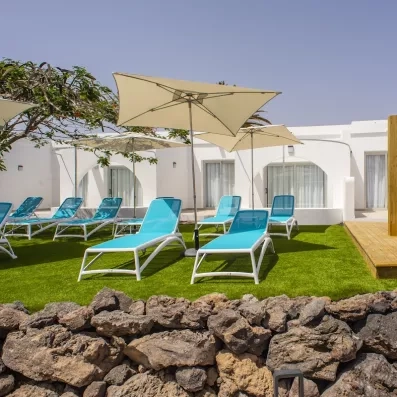 Un espace de détente ensoleillé avec des transats et des parasols disposés sur une pelouse.