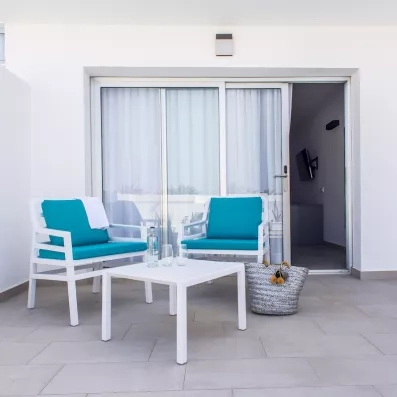 Une terrasse lumineuse, aménagée avec deux fauteuils et une table basse devant une baie vitrée.
