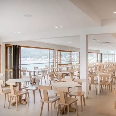 Une salle de restaurant avec des longues baies vitrées vue sur la mer.