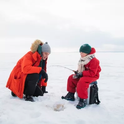 Activité de pêche blanche en famille sur un lac gelé lors d'un séjour en Laponie.