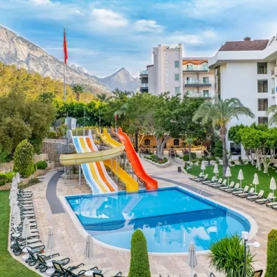 Une piscine extérieur avec quatre toboggans colorés et des transats autour.