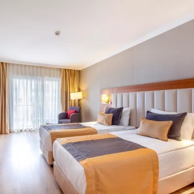 Une chambre avec deux lits doubles et une grande fenêtre.