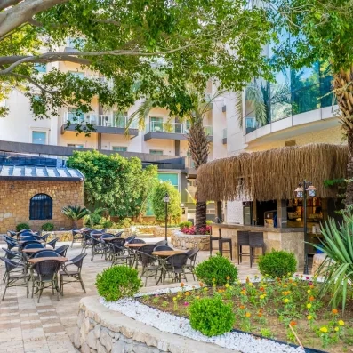 Un bar extérieur en paille avec son coin jardin, remplie de verdures.