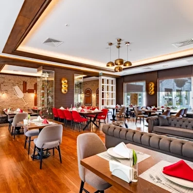Une grande salle de restaurant avec des tables et des fauteuils au fond de la salle.