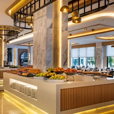 Un grand buffet placé au centre du restaurant avec différents desserts et fruits.