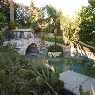 Jardin extérieur de l'hôtel avec fleuve et petit pont.