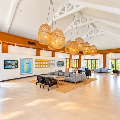 Hall de réception lumineux avec de hautes structures en bois, et des œuvres d'art colorées.