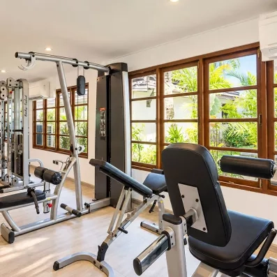 Une salle de sport lumineuse avec divers appareils face à de larges baies vitrées.