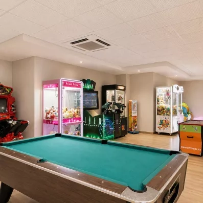 salle de jeux avec une table de billard et des machines à peluches