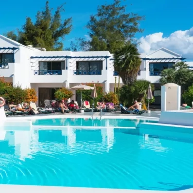 Une piscine, bordée de chaises longues et de bâtiments d'appartements blancs.
