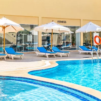 Piscine extérieure avec transats et vue sur la salle de fitness au Mondi Club Seven Seas Jolie Bay.