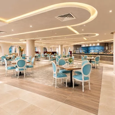 Salle de restaurant lumineuse aux fauteuils bleus du Mondi Club Seven Seas Jolie Bay à Hurghada.