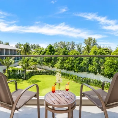 balcon avec deux chaises et une table vue sur le jardin de l'hôtel