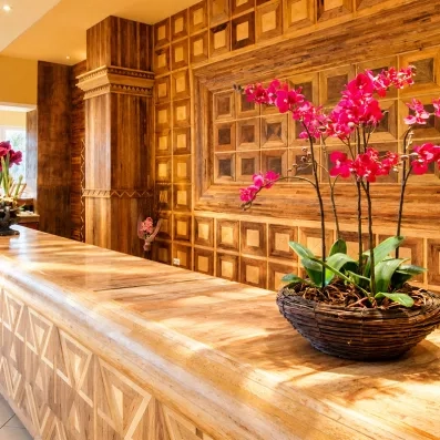 Comptoir de réception en bois sculpté avec motifs géométriques et décoration florale élégante (orchidées roses) à l'intérieur de l'hôtel.