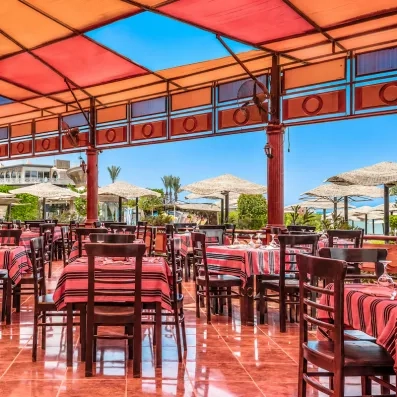 terrasse restaurant avec vue sur la piscine et parasols et tables dressées au AMC Royal à Hurghada en Egypte