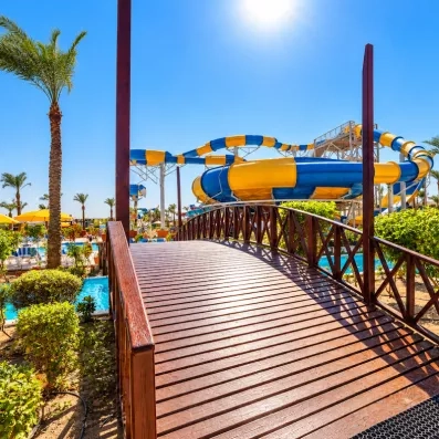 Pont en bois au-dessus du canal et toboggan aquatique jaune et bleu au Blend Club Aqua Resort