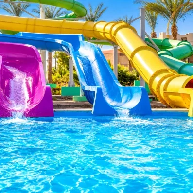 Toboggans aquatiques colorés fuchsia, bleu et jaune se jetant dans la piscine du Blend Club Aqua Resort.