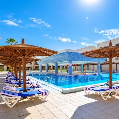 Piscine extérieure et transats avec parasols en bois à l'hôtel Blend Club Aqua Resort Hurghada Égypte