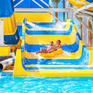 Couple glissant sur une bouée jaune sur le grand toboggan aquatique du Blend Club Aqua Resort Égypte.