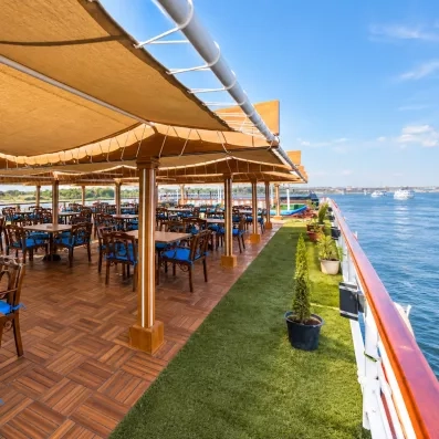 Restaurant extérieur ombragé sur le pont d'un navire, gastronomie et vue sur le fleuve Nil.