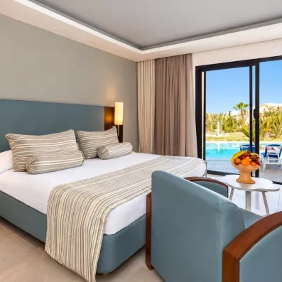 Chambre spacieuse de l'hôtel César Thalasso à Djerba avec vue imprenable sur la piscine et terrasse.
