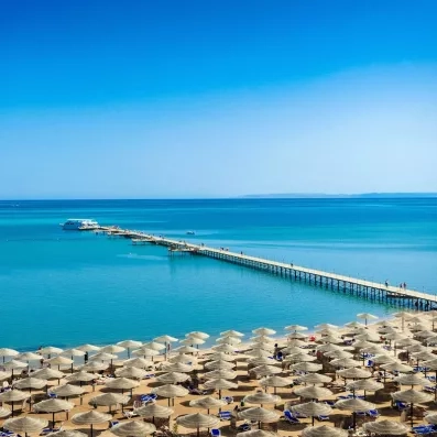 Plage privée de sable fin avec jetée surplombant la Mer Rouge à l'hôtel AMC Hurghada.