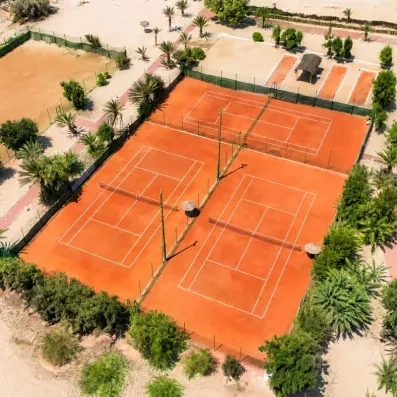 Vue aérienne des terrains de tennis en terre battue au milieu des jardins de l'hôtel à Djerba.