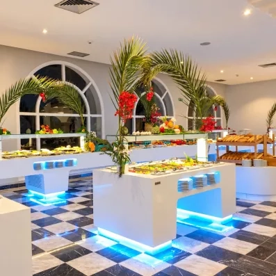 Salle de restaurant lumineuse au sol damier avec buffets garnis de spécialités culinaires à Djerba Golf.