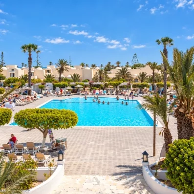 Grande piscine extérieure entourée de transats et palmiers au Djerba Aqua Resort