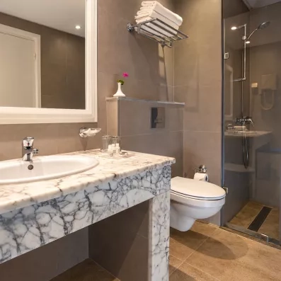 Salle de bain moderne de l'hôtel Djerba Aqua Resort avec plan vasque en marbre et douche à l'italienne.