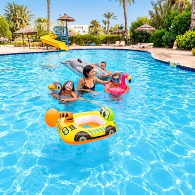 Famille s'amusant avec des bouées colorées dans la piscine extérieure avec toboggan du Djerba Resort.