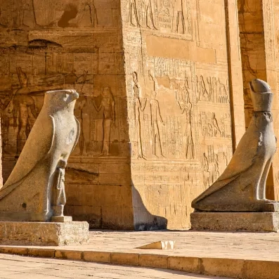 Statue du dieu faucon Horus devant les murs gravés du temple d'Edfou, escale croisière Nil.