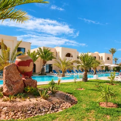 Piscine extérieure lagon entourée de palmiers et d'une architecture traditionnelle sous le soleil de Djerba.
