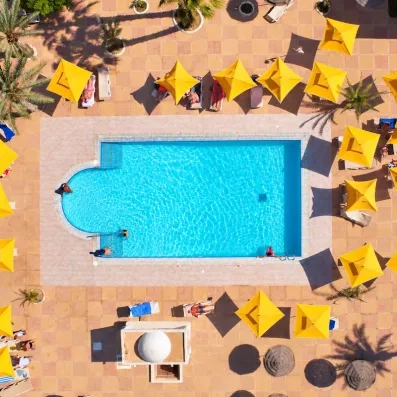 Vue aérienne d'une piscine d'eau de mer avec parasols jaunes, idéale pour la thalassothérapie à Djerba.